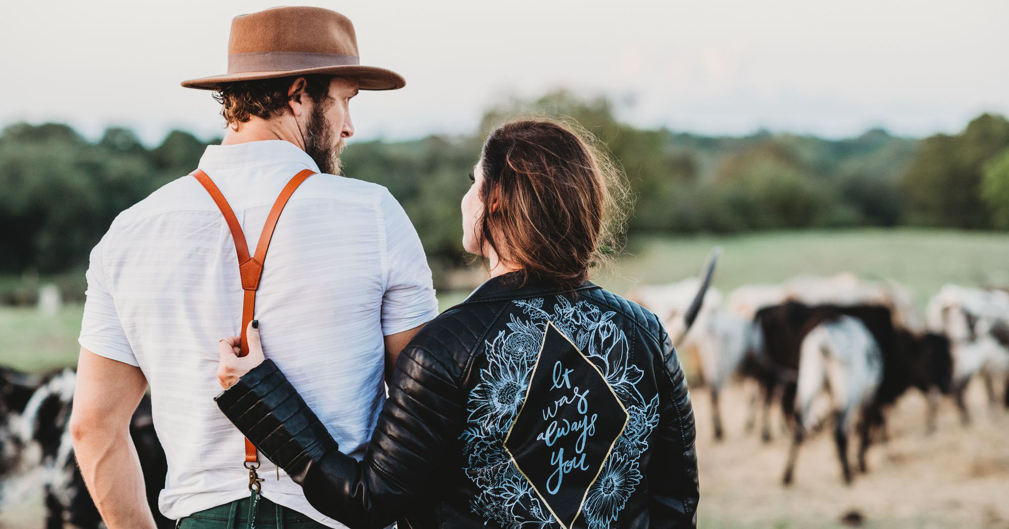 2 farmers in front of their cow herd looking at each other